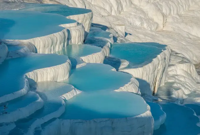 Stacked white travertine basins filled with turquoise water at Pamukkale.